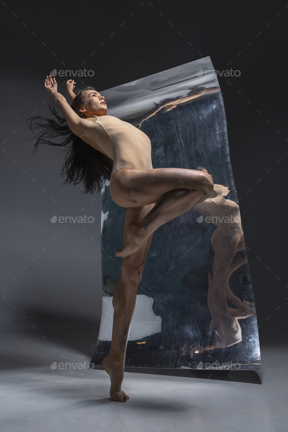 Young and stylish modern ballet dancer on grey background