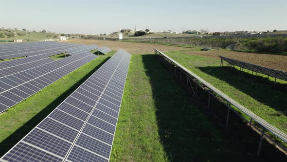 Green energy being produced on solar farm; long rows of solar panels; drone