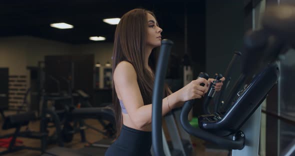 Young Attractive Athletic Sports Woman with Handsome Buttocks Doing Exercises at Elipsoid Machine in alt