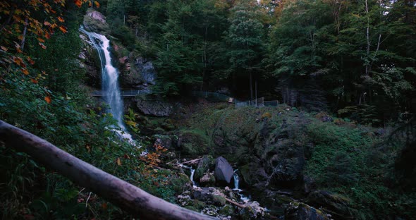 Steady side view of moody Giessbach waterfall at morning, splashing on rocks inside lush green fores alt