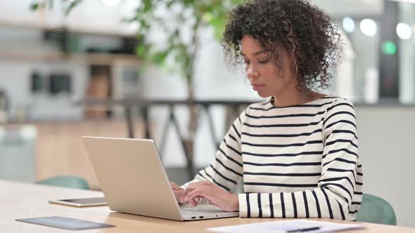 Attractive African Woman with Laptop Looking at Camera in Office alt