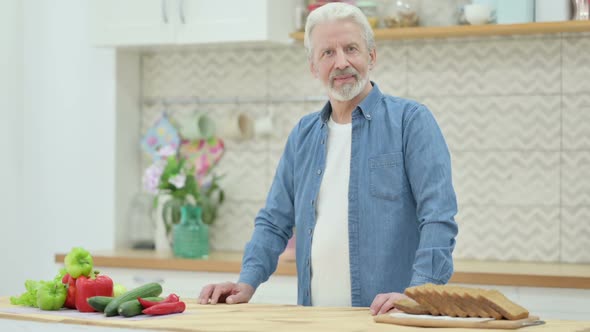 Old Man Smiling at the Camera While Standing in Kitchen alt