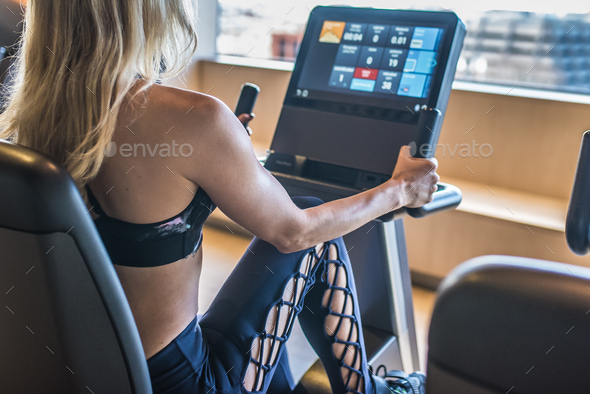 back blonde woman in the gym working out in a cycle machine