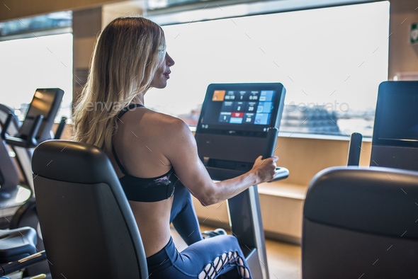 back blonde woman in the gym working out in a cycle machine