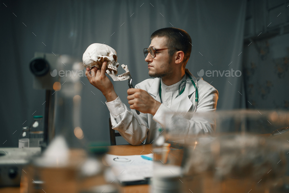 Psychiatrist in lab coat examines the human skull