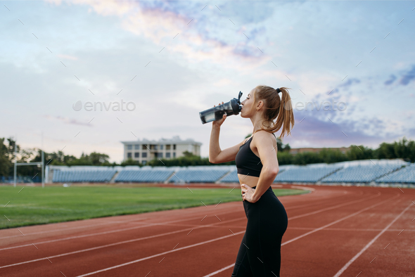 Female runner drinks water, training on stadium - Stock Photo - Images