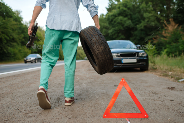 Car breakdown, man puts the spare tyre - Stock Photo - Images