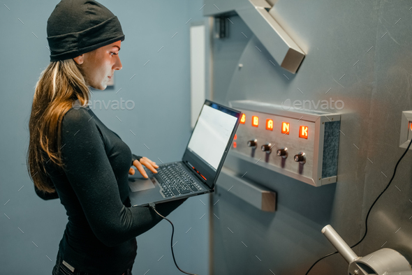 Female robber with laptop trying to open the vault