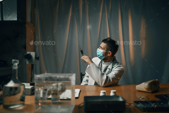 Psychiatrist in mask holding syringe with sedative
