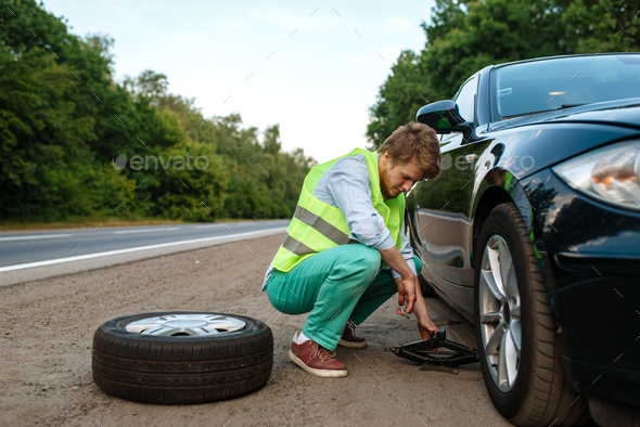 Car breakdown, young man repairing flat tyre - Stock Photo - Images