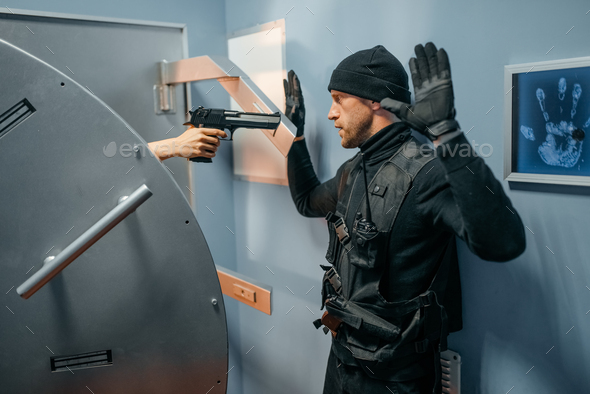 Robber standing at vault door with his hands up