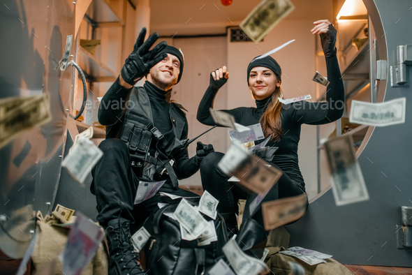 Happy robbers throwing money at the vault