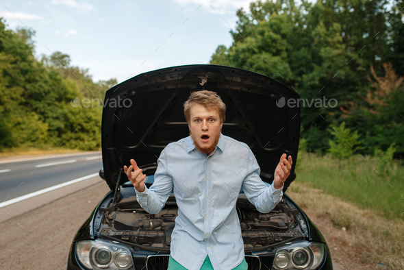 Tired young man at the opened hood, car breakdown - Stock Photo - Images
