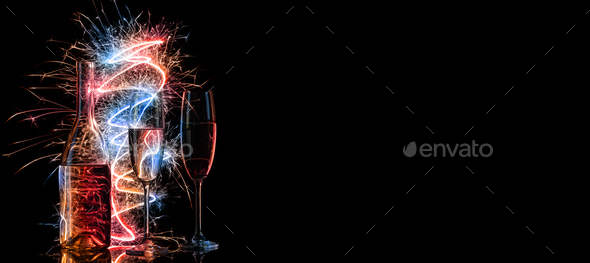 Bottle and two glasses of champagne in multi-colored sparklers on black background - Stock Photo - Images