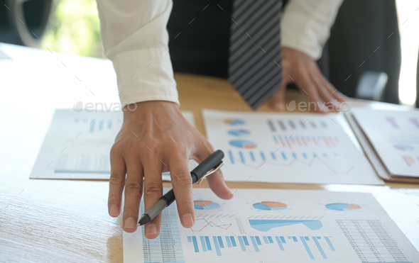 The management is checking the company earnings chart on the office desk. - Stock Photo - Images