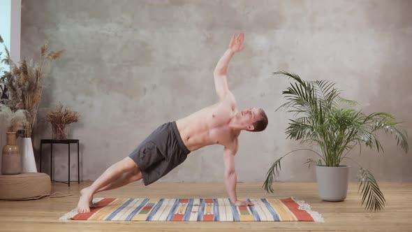 A Young European Man Works Out on the Background of the Grey Concrete Wall on a Wooden Floor alt
