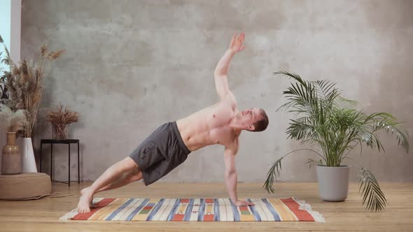 A Young European Man Works Out on the Background of the Grey Concrete Wall on a Wooden Floor