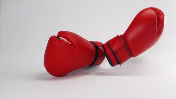 Pair of Red Leather Boxing Gloves Falling and Bouncing Isolated on White alt