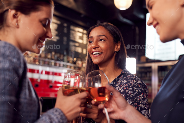 Three Women Making A Toast As They Meet For Drinks And Socialize In Bar After Work