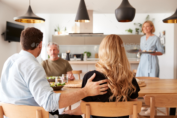 Family With Senior Parents And Adult Offspring Eating Meal Around Table At Home Together