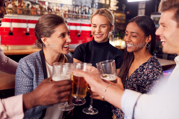Male And Female Friends Making A Toast As They Meet For Drinks And Socializing In Bar After Work