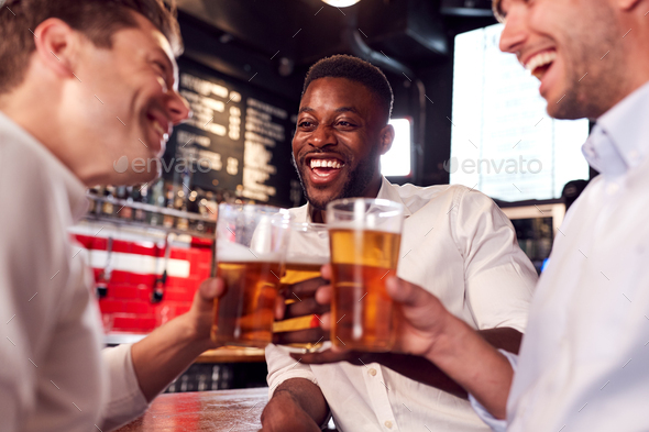 Three Men Making A Toast As They Meet For Drinks And Socialize In Bar After Work