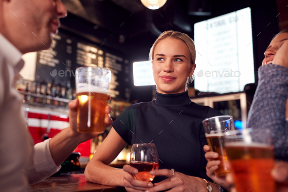 Male And Female Friends Meeting For Drinks And Socializing In Bar After Work