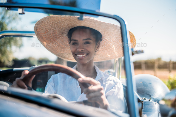 Black woman driving a vintage convertible car