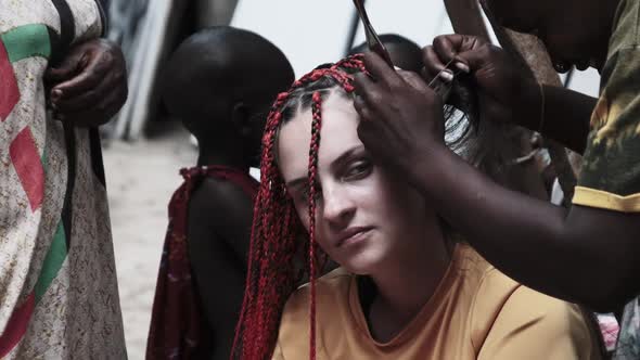 Process of Weaving African Braids with Red Kanekalon Outdoor Zanzibar Africa alt