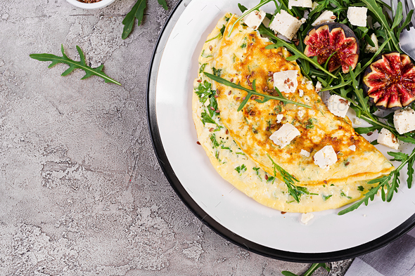 Omelette with feta cheese, parsley and salad with figs, arugula on white plate. - Stock Photo - Images