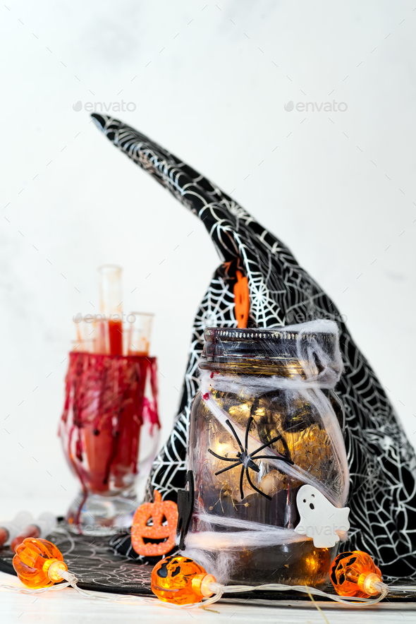 Halloween bloody glass with test tubes of tomato juice and Jar filled with orange string lights - Stock Photo - Images