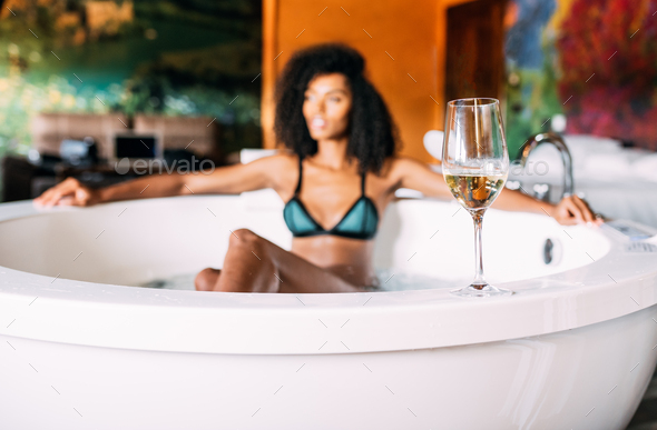 Wine glass with woman relaxing in the hydro massage bath