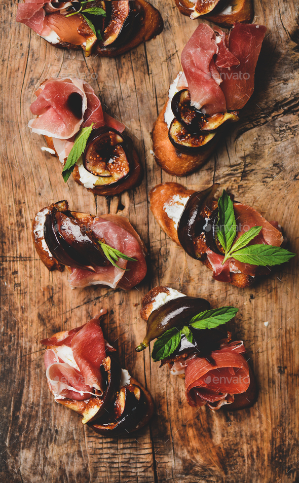 Crostini with prosciutto, goat cheese and grilled figs on board - Stock Photo - Images