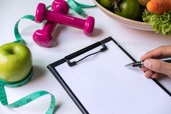 Clipboard with healthy fruit, vegetable and measuring tape on nutritionist desk