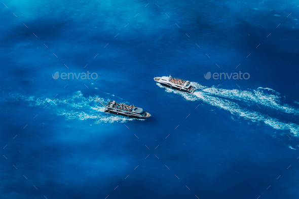 Two fully occupied tourist boats in open sea leaving and arriving in Navagio Beach on Zakynthos - Stock Photo - Images