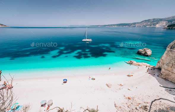 Azure water of Fteri beach, Cephalonia Kefalonia, Greece. White catamaran yacht in clear blue sea - Stock Photo - Images