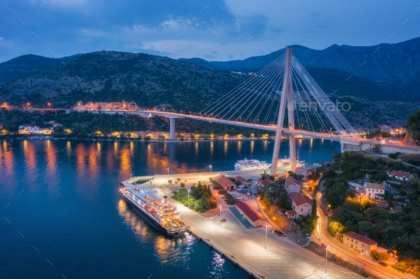 Aerial view of cruise ship at harbor and bridge at night - Stock Photo - Images
