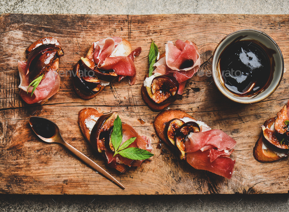 Crostini with prosciutto, cheese and figs on wooden board - Stock Photo - Images