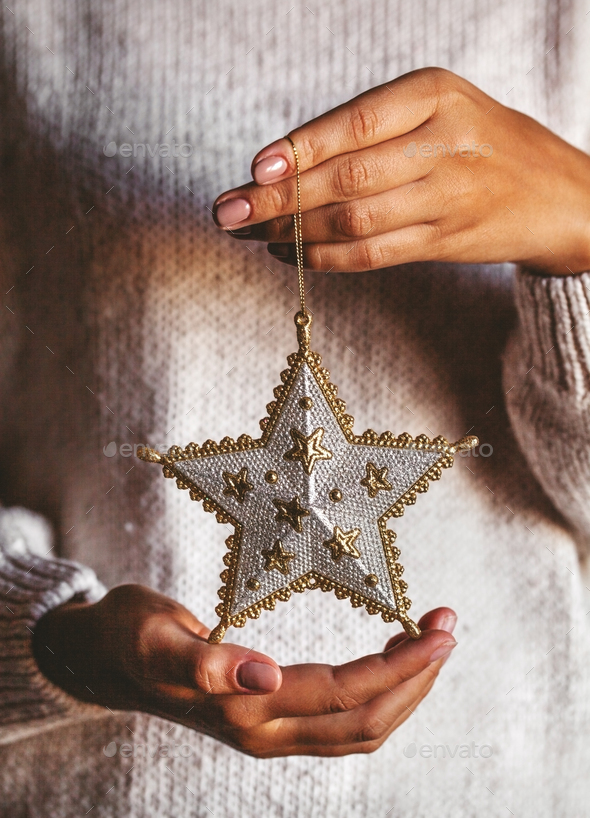 Woman in warm woolen sweater holding toy glass decorative star in hands, copy space, square - Stock Photo - Images
