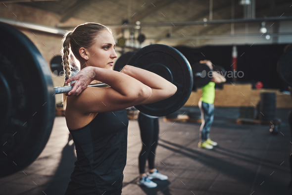 Woman pulling up large barbell in fitness class - Stock Photo - Images