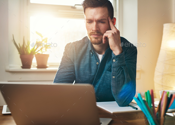 Frowning businessman reading data on his laptop - Stock Photo - Images