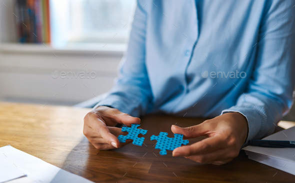 Close up of hands assembling two puzzle pieces - Stock Photo - Images