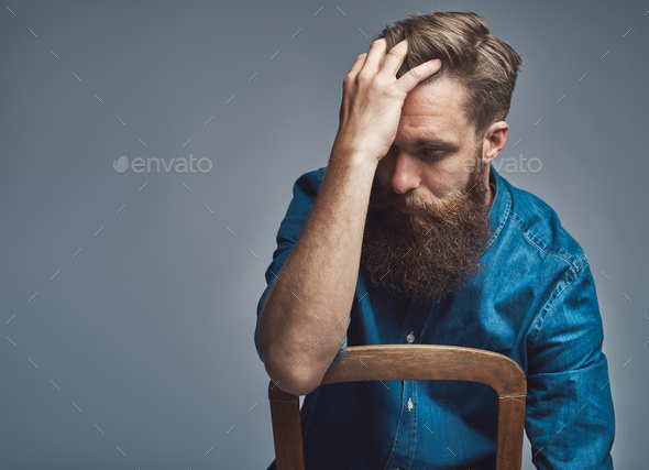Depressed man with hand on forehead over gray - Stock Photo - Images