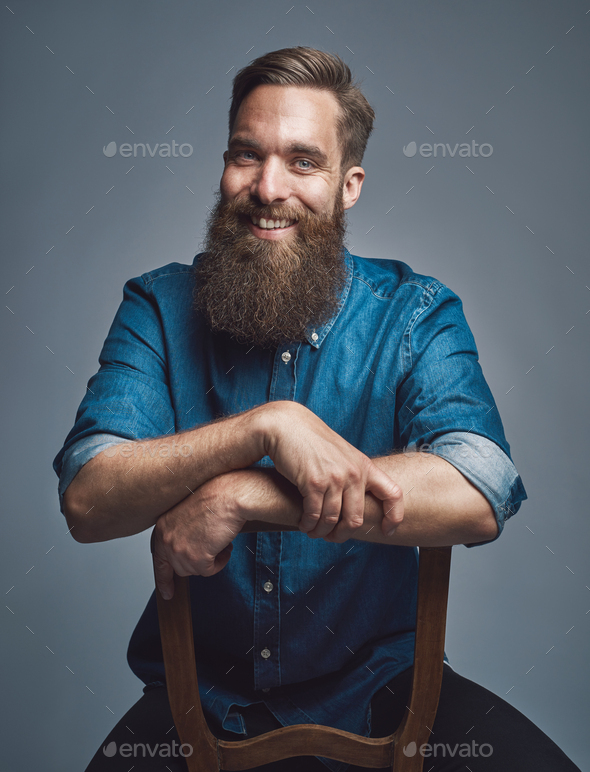 Laughing man with arms on back of chair over gray - Stock Photo - Images