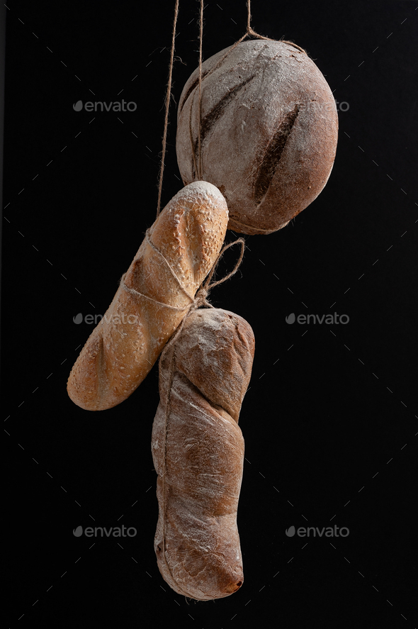 Fresh bread of various shapes hanging on the ropes on a black ba - Stock Photo - Images