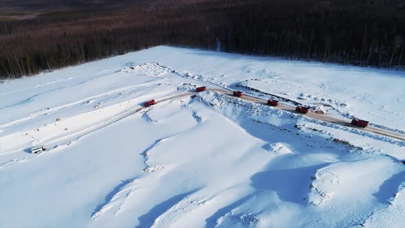 Aerial View of the Dump Trucks on on Snowy Road Arriving To Construction Site