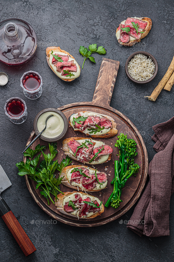 Bruschetta with roast beef, mayo and greens leaves on wooden board