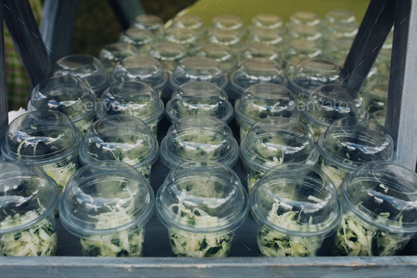 Organic veggies in cups to go.Close-up of loads of plastic cups filled with chopped vegetables and - Stock Photo - Images