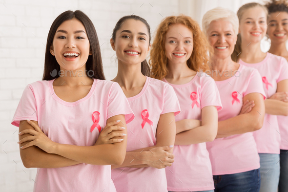 Women In Breast Cancer T-Shirts Standing Next To White Wall