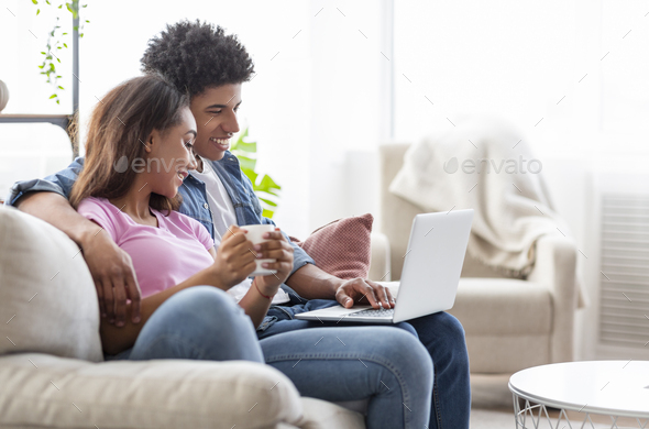 Happy couple sitting on couch watching movie on laptop - Stock Photo - Images